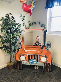 a child in an orange jeep driving through a room