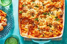 a casserole dish filled with pasta, meat and veggies on a blue table