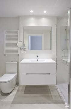 a white bathroom with a toilet, sink and shower