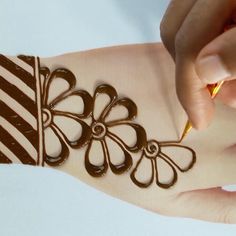 a woman is painting her hand with chocolate designs on it's arm and wrist