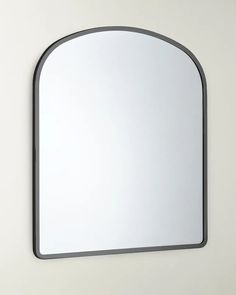 a mirror mounted to the side of a wall next to a white wall with a black frame