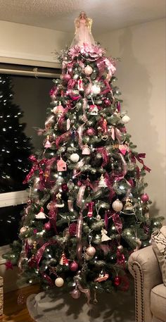 a decorated christmas tree with pink and white ornaments in a living room area next to a window