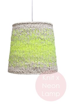 a green and white knitted lamp shade hanging from a ceiling fixture on a white wall