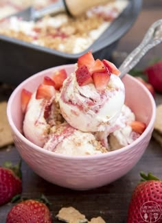 a pink bowl filled with ice cream and strawberries next to crackers on the table