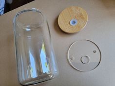 a glass jar with a wooden lid next to a plastic object on a counter top