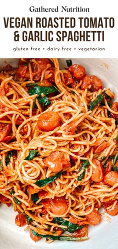 a white plate topped with pasta covered in tomato sauce and spinach leafy greens