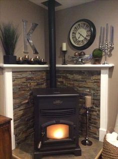 a fireplace with a clock on the wall above it and candles in front of it