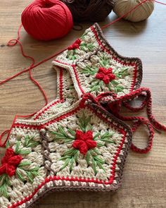 two crocheted christmas stockings sitting on top of a table next to balls of yarn