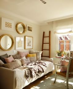 a living room filled with furniture and pictures on the wall next to a ladder in front of a window