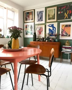 a dining room table with chairs and pictures on the wall