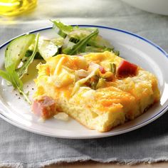 a white plate topped with an omelet next to a salad