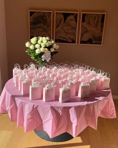 pink and white bags are sitting on a table with flowers in the vase behind them