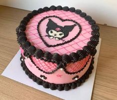 a heart shaped cake on top of a white paper with pink and black icing