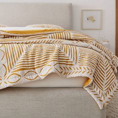 a bed with a yellow and white blanket on top of it