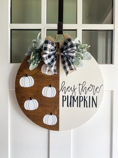 a wooden sign hanging on the side of a door with pumpkins painted on it