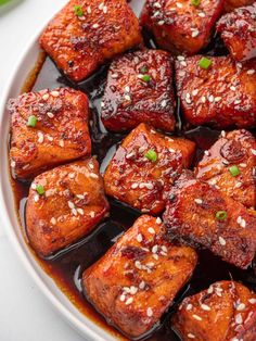 a white plate topped with tofu covered in sauce and garnished with green onions