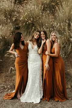 four bridesmaids pose for a photo in front of some tall grass