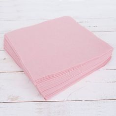 pink napkins stacked on top of each other in front of a white wooden background