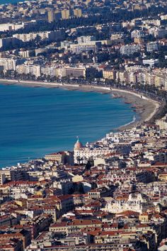 an aerial view of a city by the ocean with buildings and water in the foreground