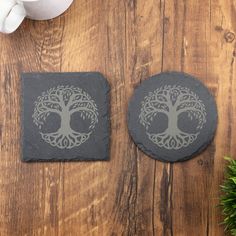 two stone coasters sitting on top of a wooden table next to a potted plant