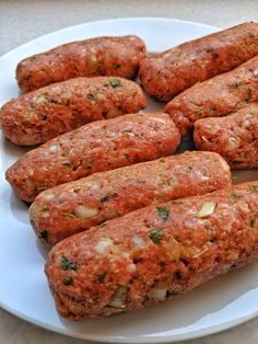 several sausages are on a white plate