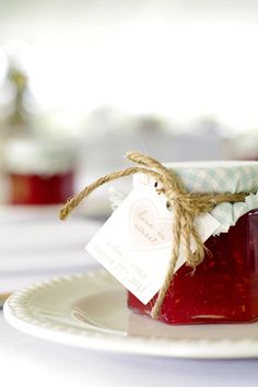 a jar filled with jam sitting on top of a white plate next to a tag