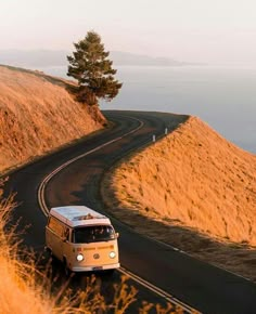 an old vw bus driving down the road by the ocean in california, usa