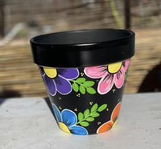 a black cup with colorful flowers painted on it