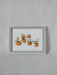 a white frame with some small pumpkins on the vine and leaves hanging from it