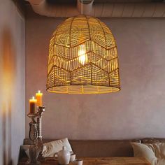 a bamboo light hanging from the ceiling over a dining room table with two candles on it