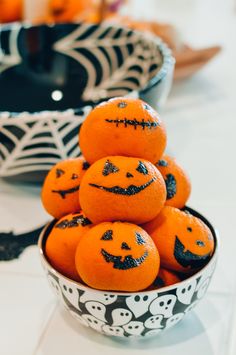 a bowl filled with oranges decorated like jack - o'- lantern pumpkins