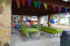 an outdoor area with tables, benches and balloons on the ceiling for people to sit down