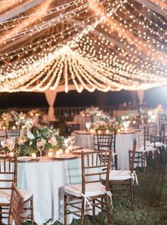 an outdoor tent with tables and chairs covered in lights