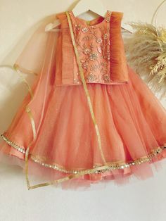 "✨ Dazzle and shine with our stunning burnt orange lehenga choli, perfect for your little one's special occasion!\" ✨ This Stunning Burnt Orange Lehenga Choli with chunni is a perfect choice for any special occasion. The skirt and top are made from full glitter net fabric, giving a gorgeous shimmering effect that will make your little one stand out from the crowd. The burnt orange color of the lehenga is bold and eye-catching, creating a striking contrast with the glittering net fabric. The choli, or blouse, is designed with a comfortable fit that feels gentle against the skin. ✨ This Lehenga Choli is perfect for any special occasion, such as weddings, parties, or eid festivals. It is also easy to customize for any size, ensuring a comfortable and secure fit for your little one. The skirt Burnt Orange Lehenga, Lehenga Choli Traditional, Indian Dresses For Girls, Kids Lehenga Choli, Orange Lehenga, Kids Lehenga, Traditional Indian Dress, Peach Dress, Skirt And Top