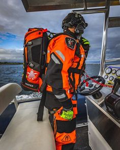 a man in an orange life jacket standing on a boat looking out at the water