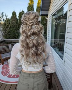 the back of a woman's head with long hair and flowers in her hair