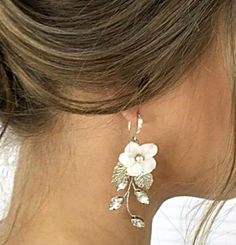 White flower dangle earrings with silver leaves. Boho bridal earrings with flower and rhinestones. Crystal vine earrings for bride or bridesmaids. Floral earrings for wedding. More items from my shop: https://www.etsy.com/shop/JewelryforbridesShop?ref=seller-platform-mcnav The diameter of the flower is 2.5 cm (1 inch). The base of the earrings is made with jewelry wire which is very flexible and at the same time it holds its shape very well being very durable. DIMENSIONS : Without hook: 2 " ( 5 cm ) With hook: 2,5"( 6,5 cm ) . Earrings is perfect choice not only for a bride but also for bridesmaids. CARE INSTRUCTIONS:  Do not spray hairspray on the accessory! IMPORTANT: For hygiene reasons the earrings are not refundable ! Bridesmaids Floral, Boho Bridal Earrings, Vine Earrings, Earrings For Bride, Bride Floral, Flower Dangle Earrings, Dangle Earrings Boho, Silver Leaves, Jewelry Wire