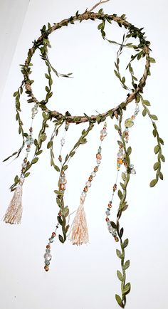 a piece of art that is made out of leaves and beads on a white surface