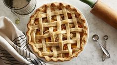 a pie sitting on top of a white plate next to utensils and a bottle