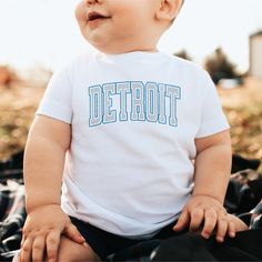 Infant Detroit football shirt for the Mini Lions Fans. This Crewneck T-shirt has a fun retro Lion graphic. It is the perfect Game Day shirt or a fun gift to show your Detroit pride. - M A T E R I A L S - 100% combed, ring-spun cotton (fiber content varies for different colors) Light fabric (4.5 oz/yd² (153 g/m Classic fit - S I Z I N G - Please have a look at our sizing chart listed in the product photos for sizing recommendations. For a looser fit please size up. - C A R E  I N S T R U C T I O White Retro T-shirt For Fans, White Retro T-shirt For Fan Gear, Retro White T-shirt With Team Name, Retro Cotton T-shirt With Name Print, Detroit Game, Football Apparel, Lion Graphic, Cute Fall Shirt, Lions Football