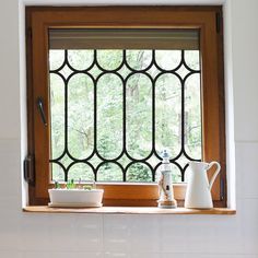 a kitchen window with pots and panes on the windowsill, in front of a white tiled wall