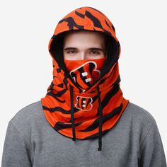 Oh, the weather outside is frightful. But bundling up in the Cincinnati Bengals Alternate Team Color Drawstring Hooded Gaiter? That's oh, so delightful. Features All-over alternate team-colored design so you can rep the team in style Bold team logo display on front face cover and miniature team logo display on scarf, in case there were any doubts where your allegiances lie Drawstring closure to keep you secure Multifunctional, can be utilized as a face cover, neck gaiter, and snood Versatile - p Sports Balaclava With Adjustable Hood, Winter Sports Hoodie With Drawstring, Casual Sports Balaclava Hooded, Casual Hooded Balaclava For Sports, Winter Sports Event Hoodie With Drawstring Hood, Winter Sports Fan Hoodie, Winter Outdoor Hoodie With Drawstring, Casual Balaclava With Drawstring Hood For Outdoor, Team-colored Sports Fan Hoodie For Winter