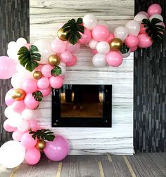 the balloon arch is decorated with pink, white and gold balloons in front of a fireplace