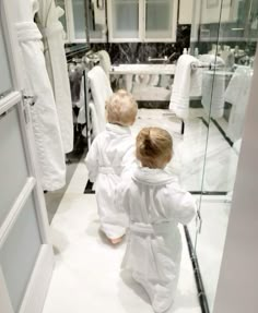 two children in bathrobes looking into a bathroom mirror