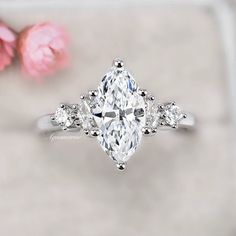 an oval cut diamond ring with three pear shaped diamonds on the band and side stones