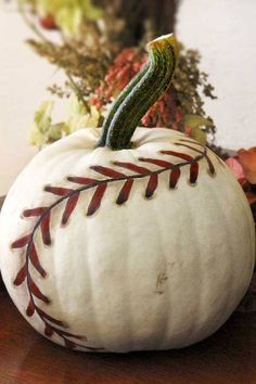 a white pumpkin with a baseball painted on it's side sitting on a table