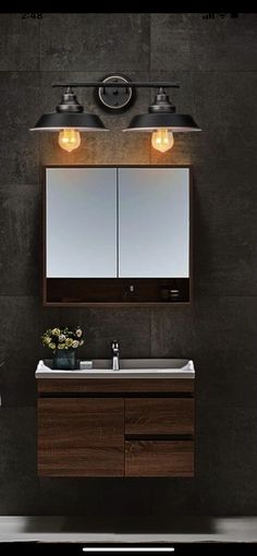 a bathroom vanity with two lights above it and a mirror on the wall next to it