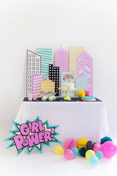 a table topped with cake and balloons next to a sign that says girl power on it