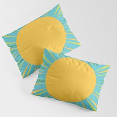 two blue and yellow pillows with sun design on the front one has a gold circle in the middle