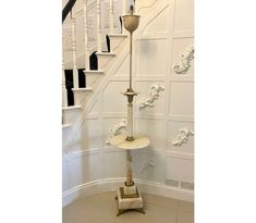 an old fashioned lamp stands in the corner of a room with white walls and stairs